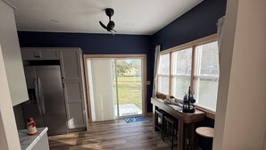 Una cocina moderna con piso de madera, un refrigerador y un comedor con un taburete de bar.