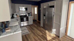 Una cocina moderna con armarios blancos, electrodomésticos de acero inoxidable y suelo de madera.