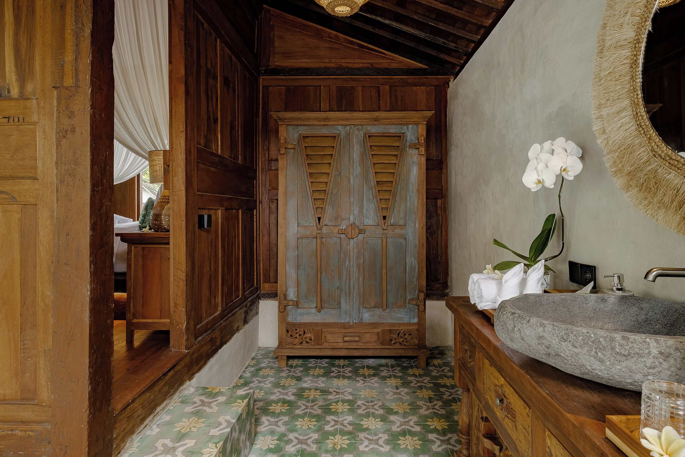 A bathroom with a stone sink, wooden vanity, and a large mirror.