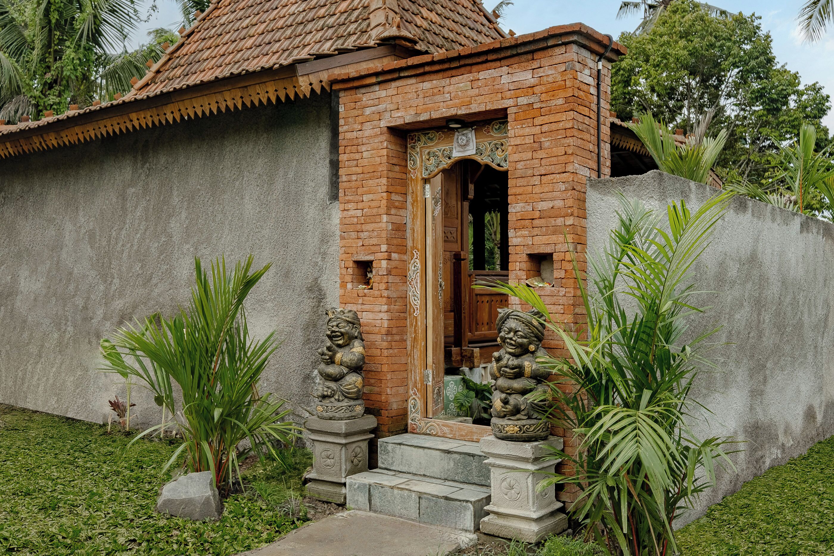 A small brick building with a tiled roof, a wooden door, and two stone lion statues at the entrance.