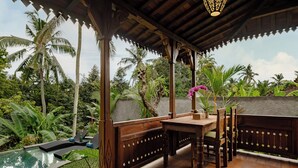 Una terraza de madera con piscina, rodeada de exuberante vegetación tropical.
