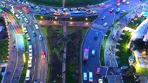 Une vue aérienne d’un carrefour giratoire doté de nombreuses voies d’entrée et de sortie, entouré d’immeubles de grande hauteur et traversé par une circulation intense.