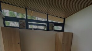 Une chambre moderne avec un grand lit, une tête de lit en bois, des étagères intégrées et une vue sur les palmiers par la fenêtre.