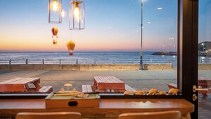 A seaside view from a restaurant with wooden tables and hanging light fixtures. - Donghae Il Mare Pension (Donghae)