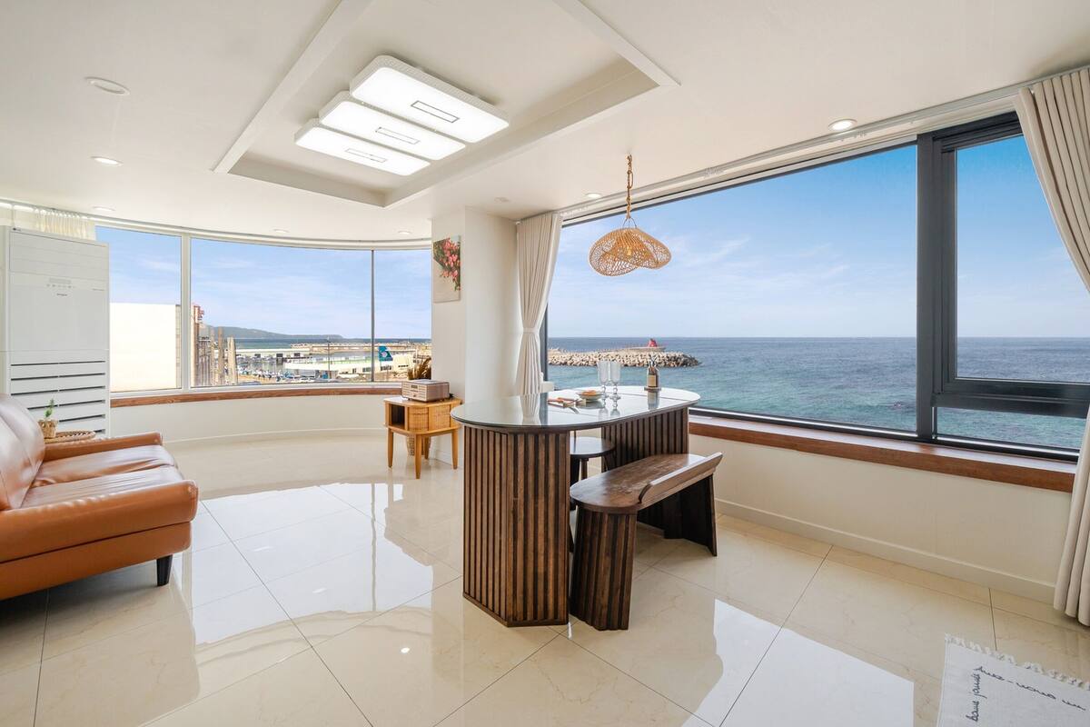 Een moderne woonkamer met een groot raam met uitzicht op zee.