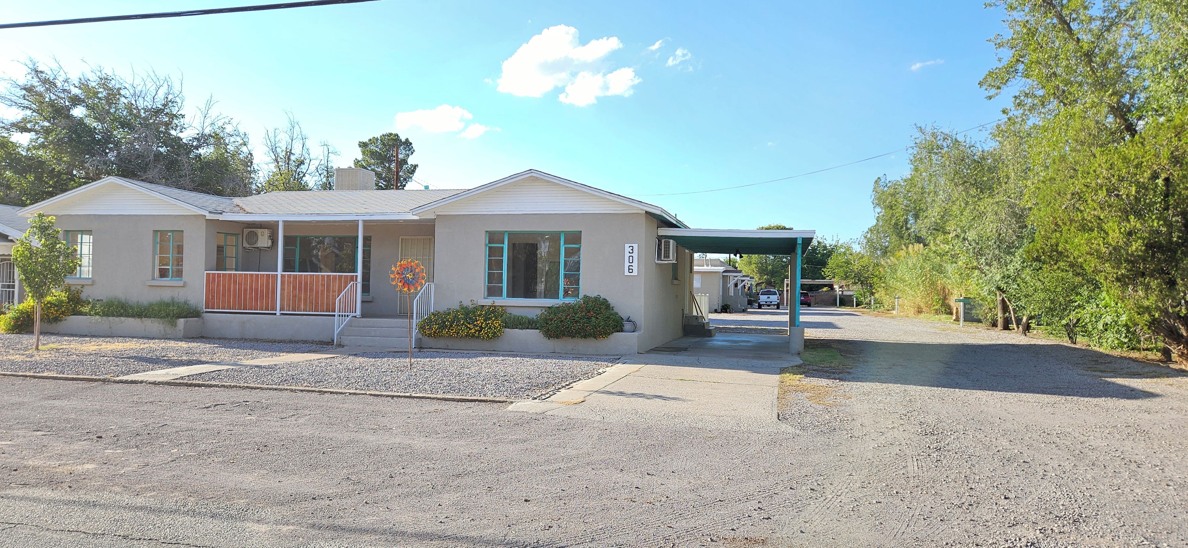 A single-story building with a covered porch, a small driveway, and a gravel parking area.