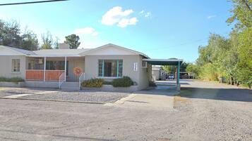 A single-story building with a covered porch, a small driveway, and a gravel parking area.