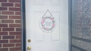A white door with a number plate '209' above it, a brass doorbell, and a welcome sign with floral decorations. - Riverside Lodge (Clarendon)
