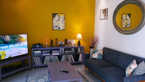 Een woonkamer met een televisie, bank, bijzettafeltje en boekenkast.