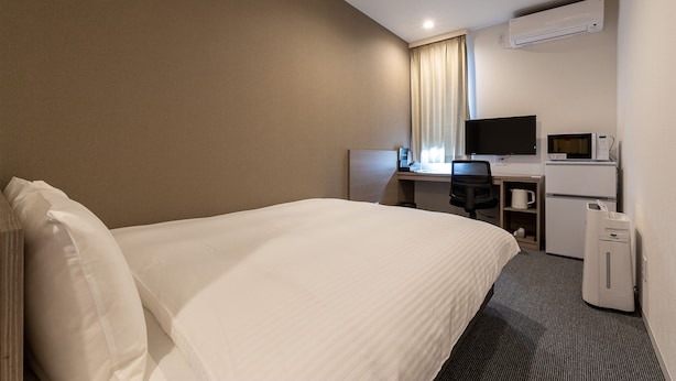 A hotel room with a bed, a desk with a computer, a television, and a microwave. - HOTEL R9 The Yard Mokaaramachi (Mooka)