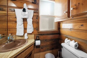 A wooden bathroom with a sink, mirror, and toilet.