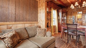 A wooden interior with a sofa, dining table, and chairs. - Big Bear Cabin (Big Bear Lake)