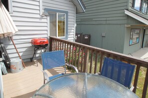 A covered outdoor area with a table and chairs, a barbecue grill, and a trash can.