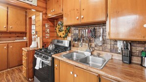 A kitchen with wooden cabinets, a stainless steel sink, and a stove. - Big Bear Cabin (Big Bear Lake)