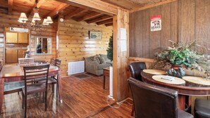 A wooden interior with a dining area, a sofa, and a Christmas tree. - Big Bear Cabin (Big Bear Lake)