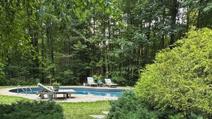 Zona de piscina con sillones de descanso, una piscina pequeña y plantas en macetas.