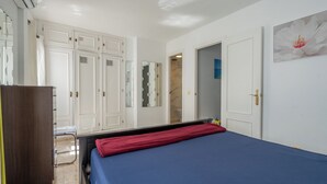 Une chambre à coucher comprenant un lit, une armoire, un miroir et une porte donnant sur une salle de bain.