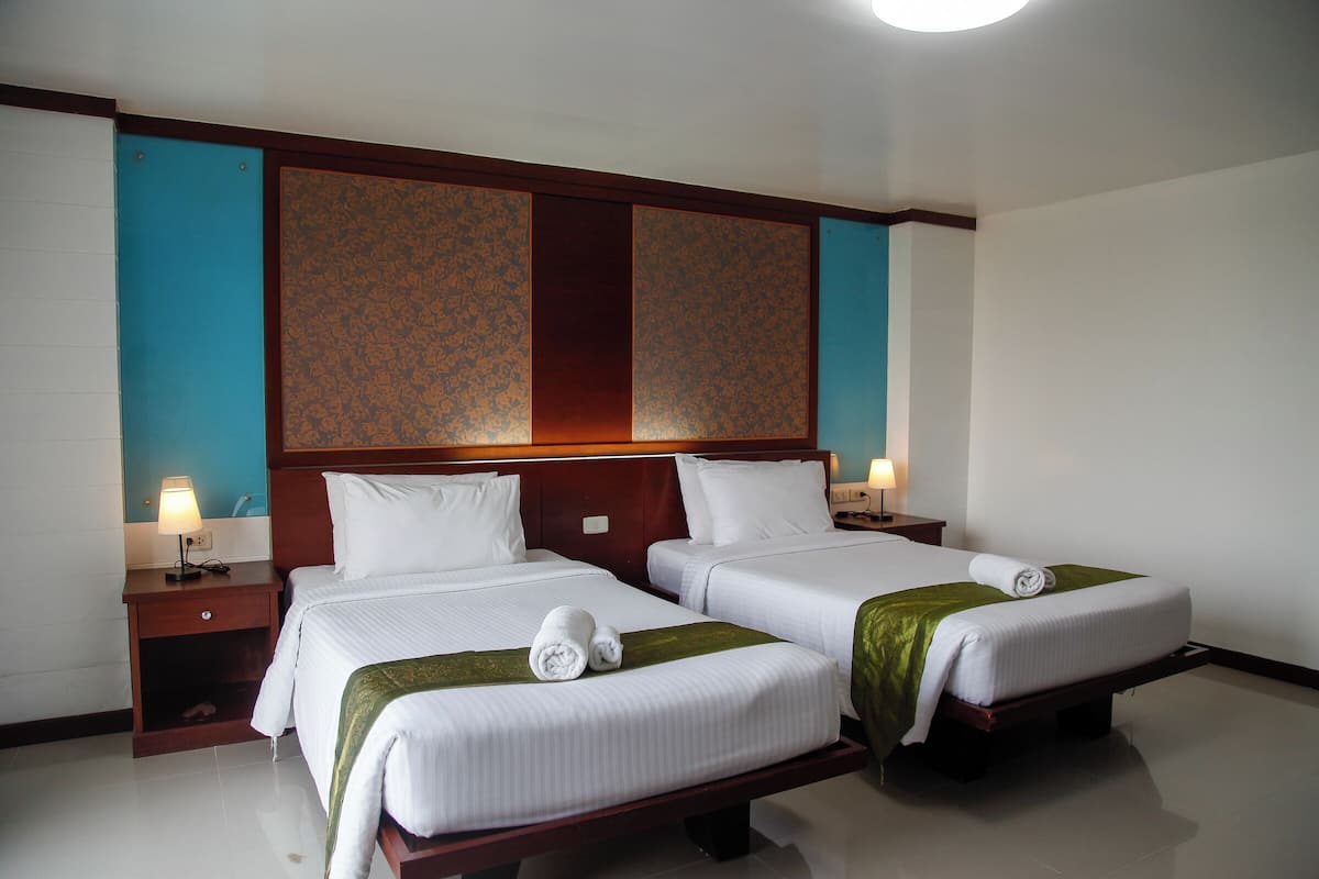 Ein Hotelzimmer mit zwei Betten, einem Holzkopfteil und einem Nachttisch mit Lampe.