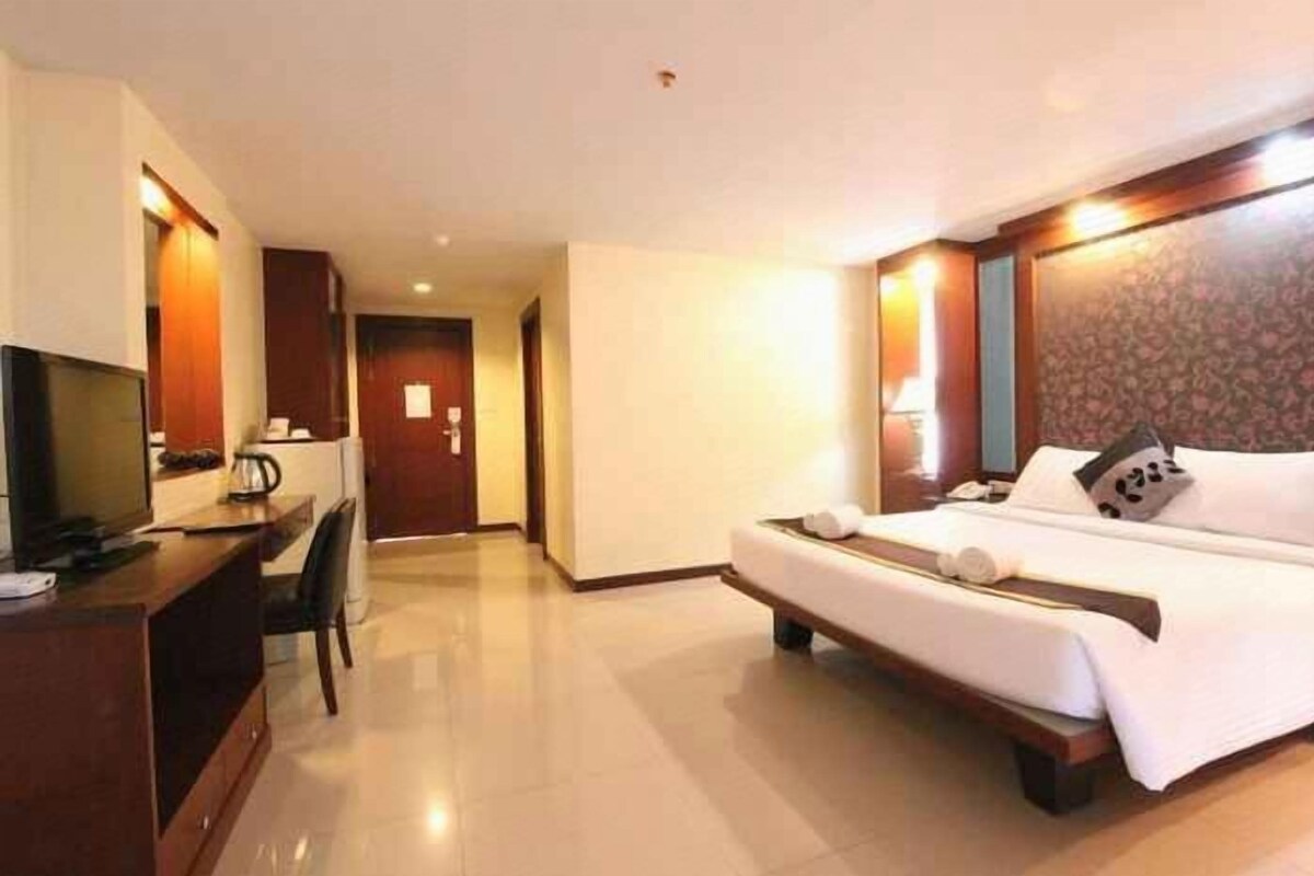 Une chambre d’hôtel comprenant un lit, un bureau, une télévision et une porte donnant sur une autre pièce.