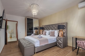 Camera da letto moderna con un letto grande, lampade da comodino, un lampadario e pavimento in legno.