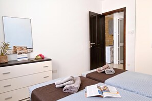 A hotel room with two beds, a dresser, a mirror, and a door leading to a bathroom.