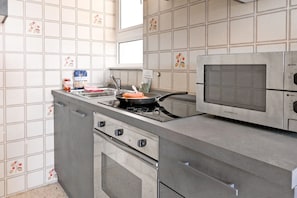 A kitchen with a stove, oven, microwave, and a sink.