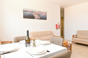 A dining area with a table set for two, a bottle of wine, and a small plant.