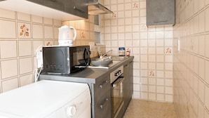 A compact kitchen with a microwave, kettle, and a small oven.