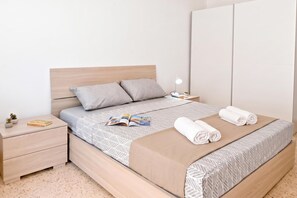 A neatly arranged hotel room with a bed, a bedside table, a lamp, and a small plant.