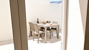 Un comedor con una mesa y sillas, una botella de vino y un bol de fruta.