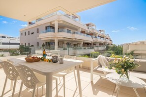 Un appartement moderne dotĂ© dâun balcon, meublĂ© avec une table, des chaises et un vase de fleurs.