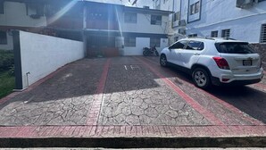 Um SUV branco estacionado em uma entrada com portão, com área pavimentada identificada com o número 15.