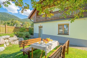Un chalet à deux étages doté d’un balcon, d’une table à manger dressée pour le petit-déjeuner et, en arrière-plan, d’un mur en pierre.