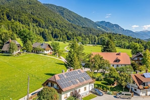 Un village rural avec des maisons, une route sinueuse et des montagnes en arrière-plan.