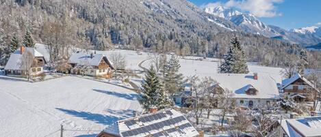 A snow-covered village with houses, a road, and mountains in the background.