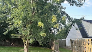 A backyard with a wooden fence, a tree, and a shed. - Point peele (Leamington)