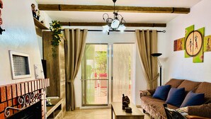 Un salón acogedor con chimenea, un sofá, una mesa de centro y vistas al exterior a través de un ventanal corredero.