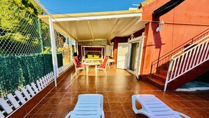 Un patio cubierto con mesa y sillas, una cerca blanca y una escalera.