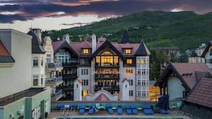 A hotel with a swimming pool, multiple balconies, and a view of a mountainous landscape. - Arrabelle Premier Penthouse - ski in/ski out (Lionshead)