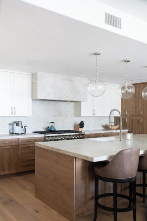 A modern kitchen with a central island, wooden cabinets, and pendant lighting. - Arrabelle Premier Penthouse - ski in/ski out (Lionshead)