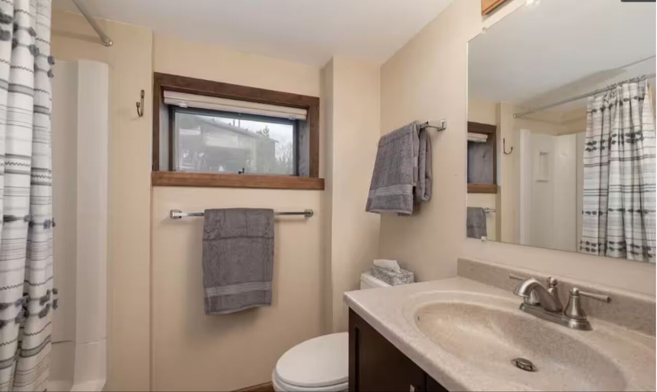 A bathroom with a toilet, sink, and window.