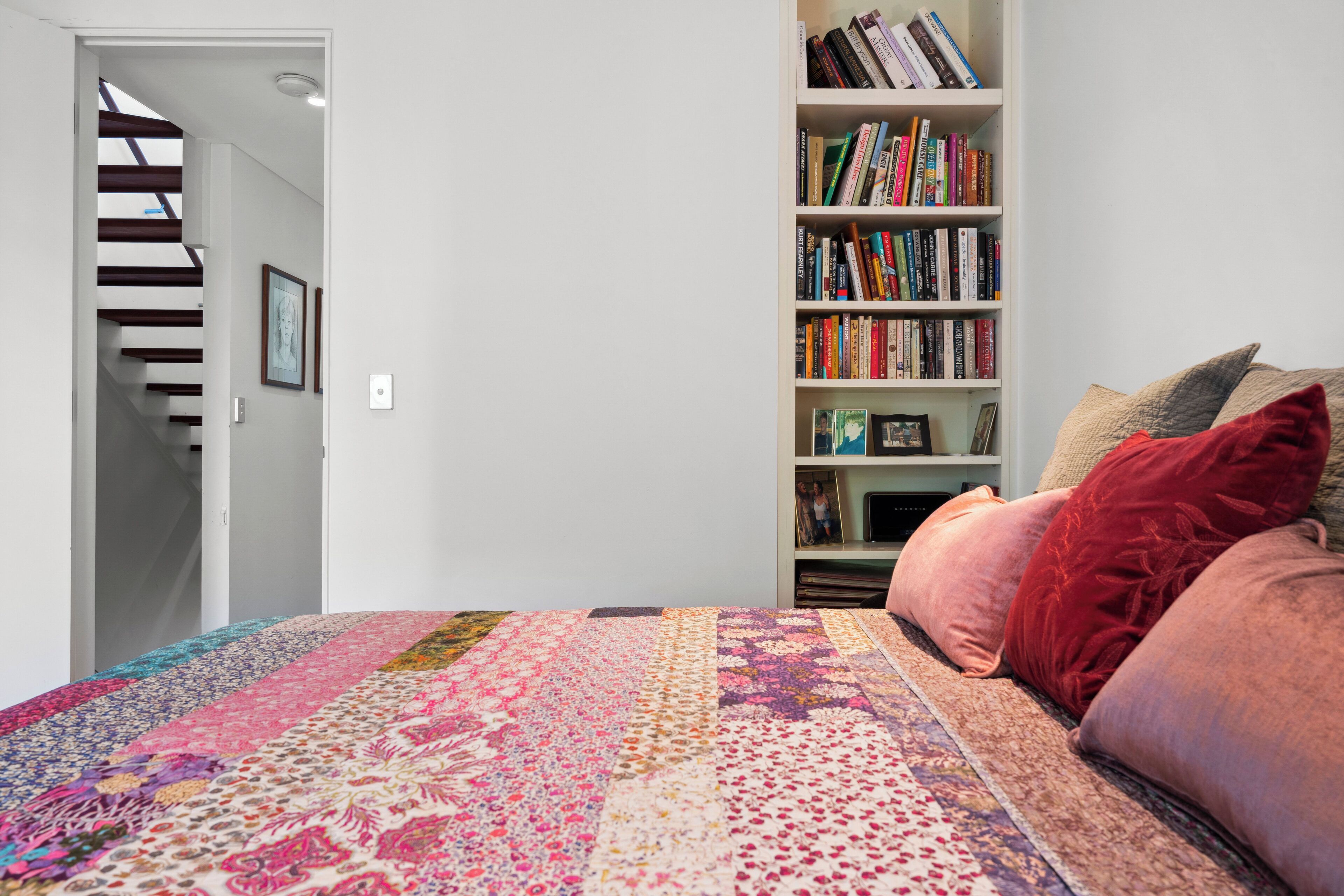 Ein Schlafzimmer mit einem großen Bett, einer Bücherwand und einer Treppe.
