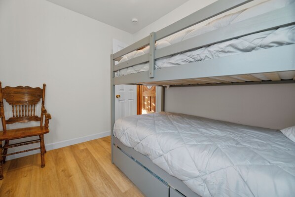 A bunk bed with a wooden chair and a door in the background.
