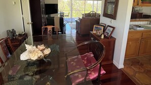 Un vaste espace dédié à la salle à manger, avec une table en verre, des chaises en bois et un ventilateur de plafond.