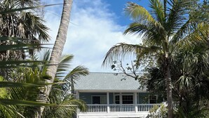 Une maison avec un garage blanc, une véranda et un chemin de briques menant à l’entrée.