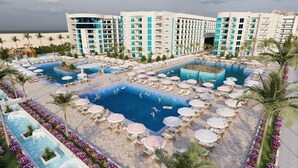 Een resort met diverse zwembaden, ligbedden en een groot gebouw op de achtergrond.