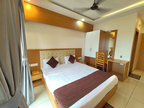 Een hotelkamer met een groot bed, een houten hoofdbord, een bureau met een stoel en een kledingkast.