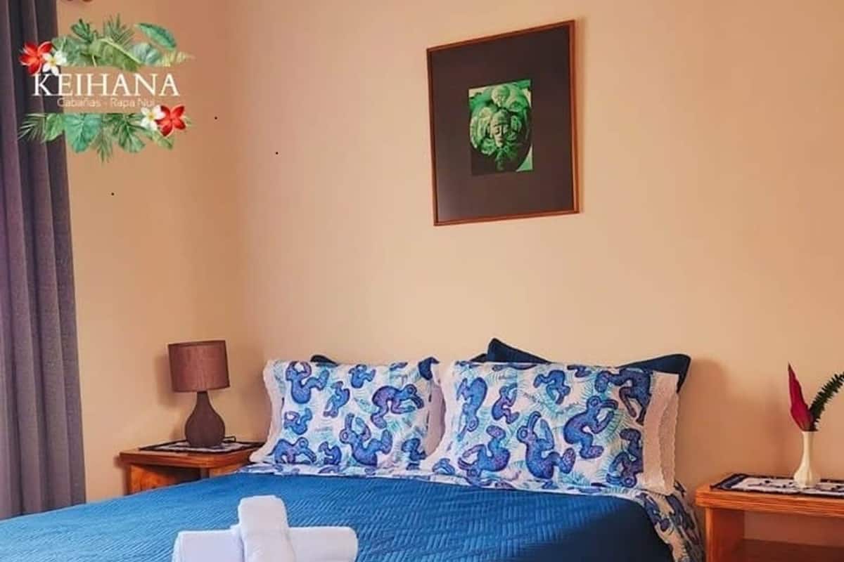 Una habitación de hotel con una cama, una mesita de noche, una lámpara y un cuadro en la pared.
