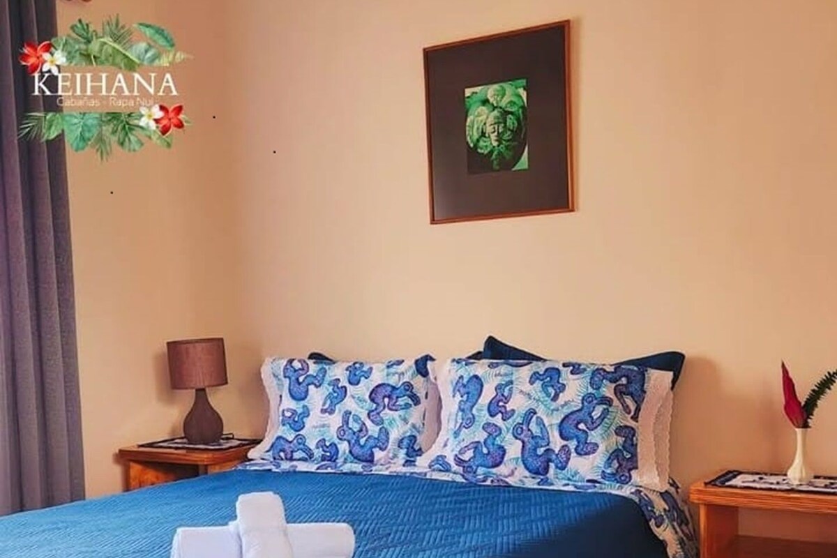 A hotel room with a bed, a nightstand, a lamp, and a framed picture on the wall.