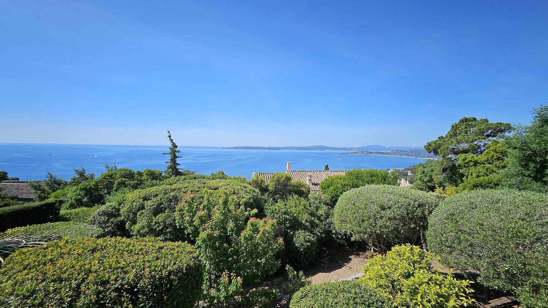 A coastal landscape with a clear view of the sea, lush greenery, and traditional architecture.